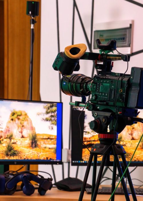 Professional video camera on a stand with monitors on a table in a studio. Virtual production